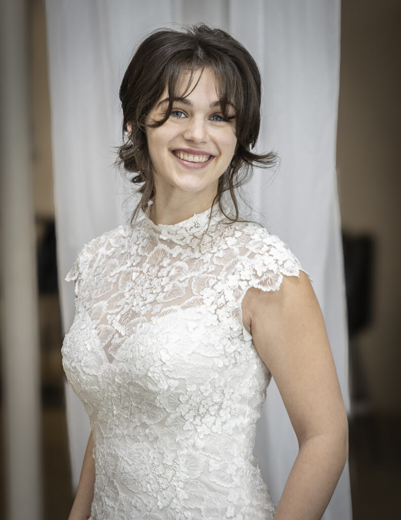 A classic elegant bride wearing a lacy, vintage-inspired wedding dress with a high neck and open back.