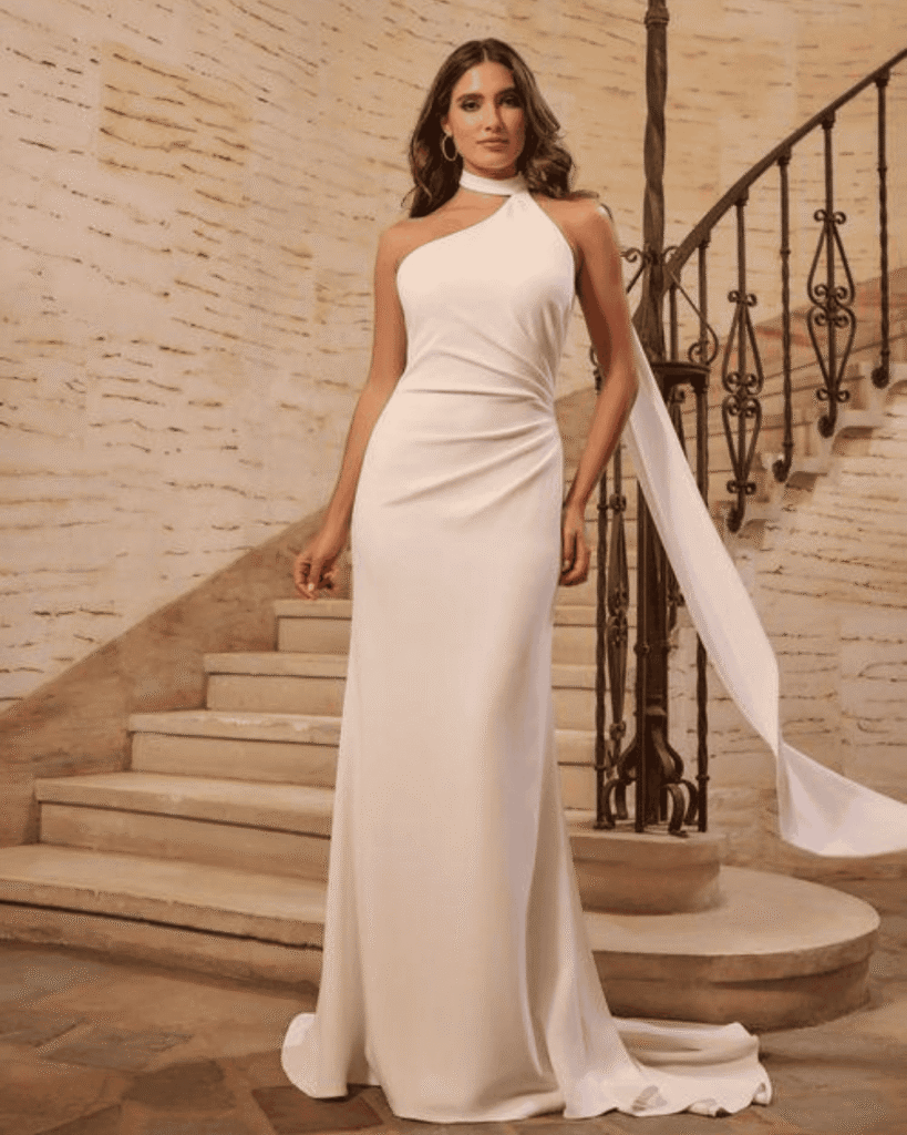 A simple modern wedding dress by EB Couture featuring a one-shoulder neckline, gathering at the side, and a scarf as an additional accessory, perfect for a modern bride.