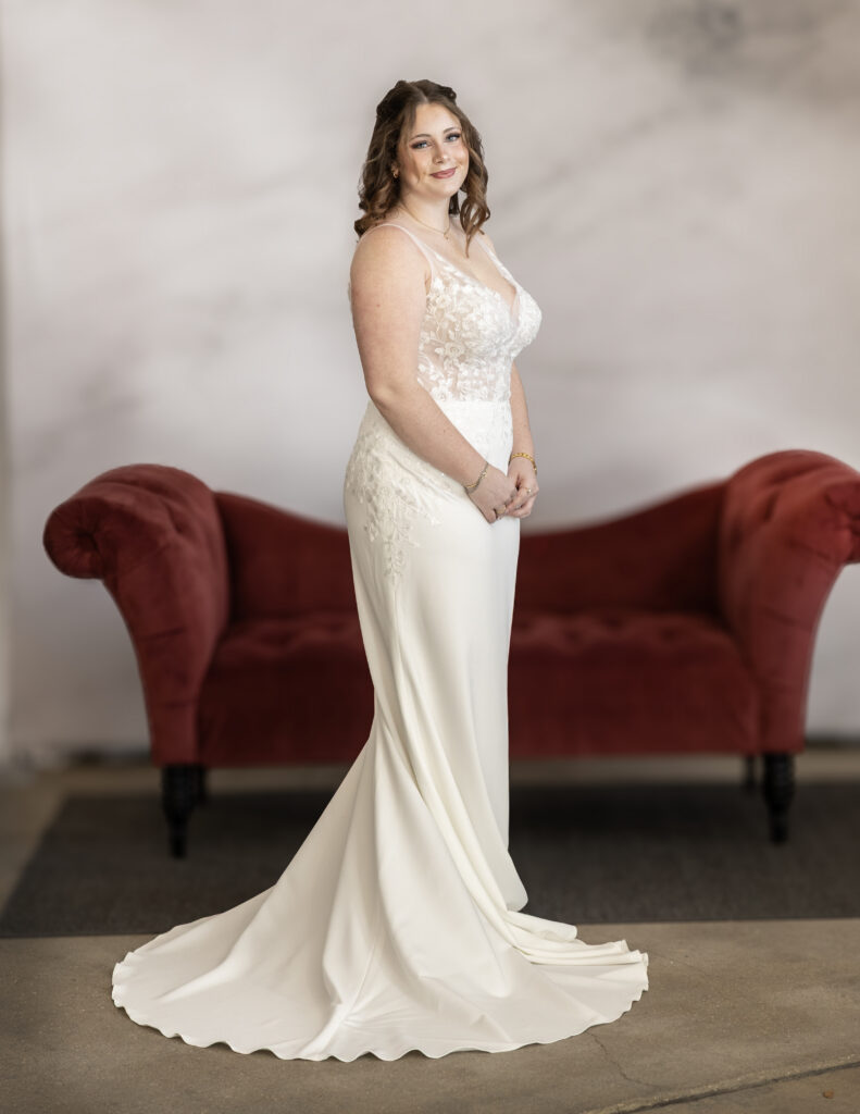 An Elegant Bride Wearing Maggie Sottero's Holly wedding dress, which features an intricate lace bodice and a simple skirt.
