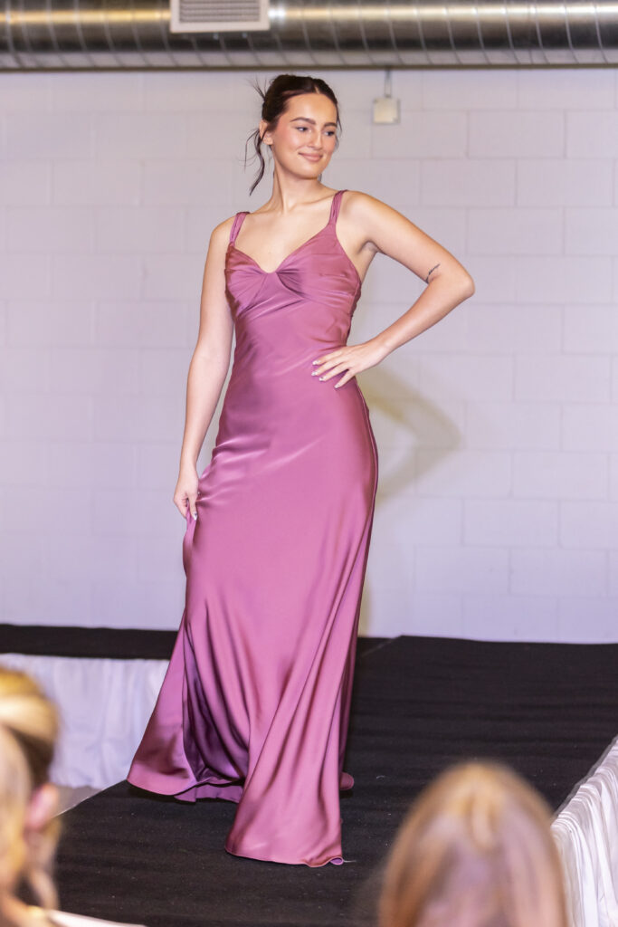 A model wearing a pink morilee bridesmaid dress from Elegant brides.